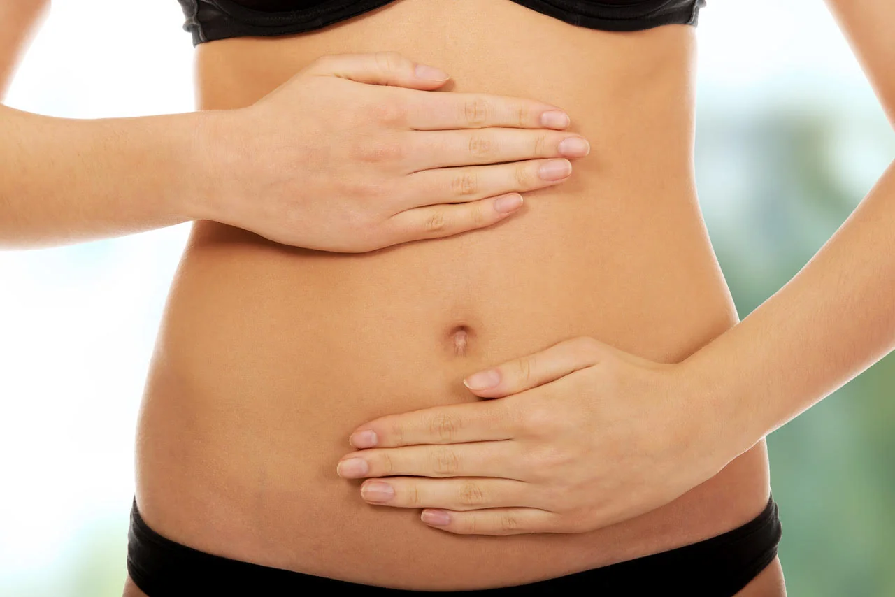 Zwei Hände liegen auf dem Bauch.